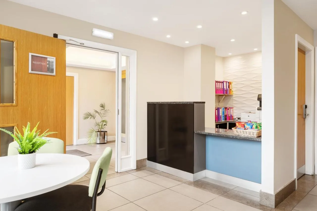 a kitchen and dining room with a white table and chairs at Rooms Inn on West Parade, Newcastle upon Tyne