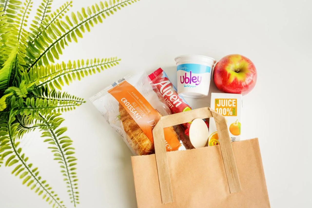 a paper bag filled with food and an apple, the complimentary breakfast bag at Rooms Inn